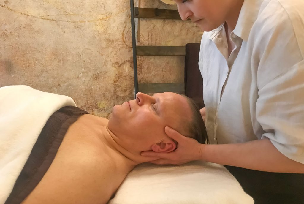 Susan Mehr behandelt den Nacken und Hinterkopf eines Kunden, indem sie mit einem kräftigen aber sanften Griff diesen Bereich in die Länge zieht
