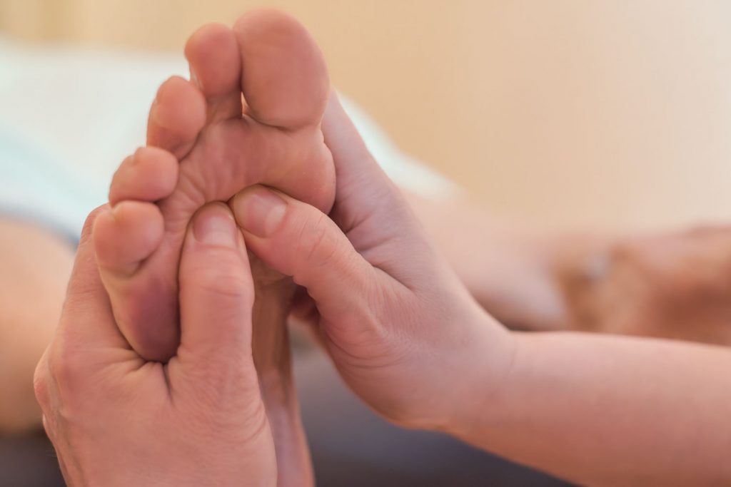 Während der Fußreflexzonenmassage stimuliert Susan Mehr mit beiden Daumen den Bereich unter den Zehen der Fußsohle mit Druck, um Verspannungen zu lösen