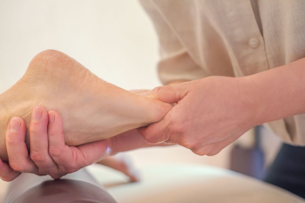 Susan Mehr behandelt den Bereich unter dem großen Zeh der Fußsohle mit einem speziellen Daumengriff, um Verspannungen während der Fußreflexzonenmassage zu lindern.