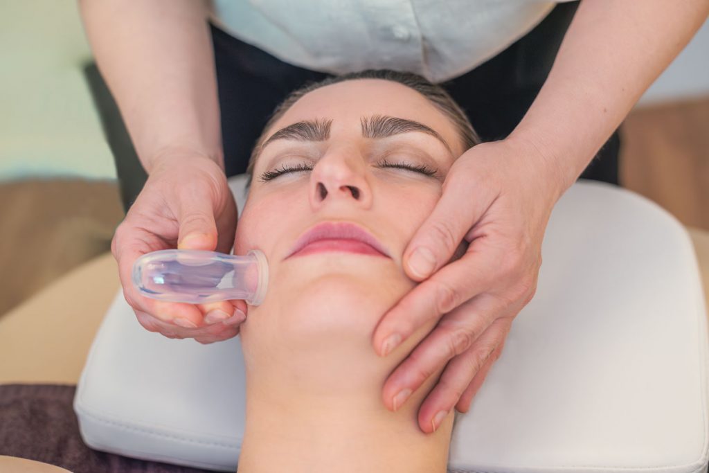Susan Mehr schröpft die Wange einer Kundin während der Schröpfmassage
