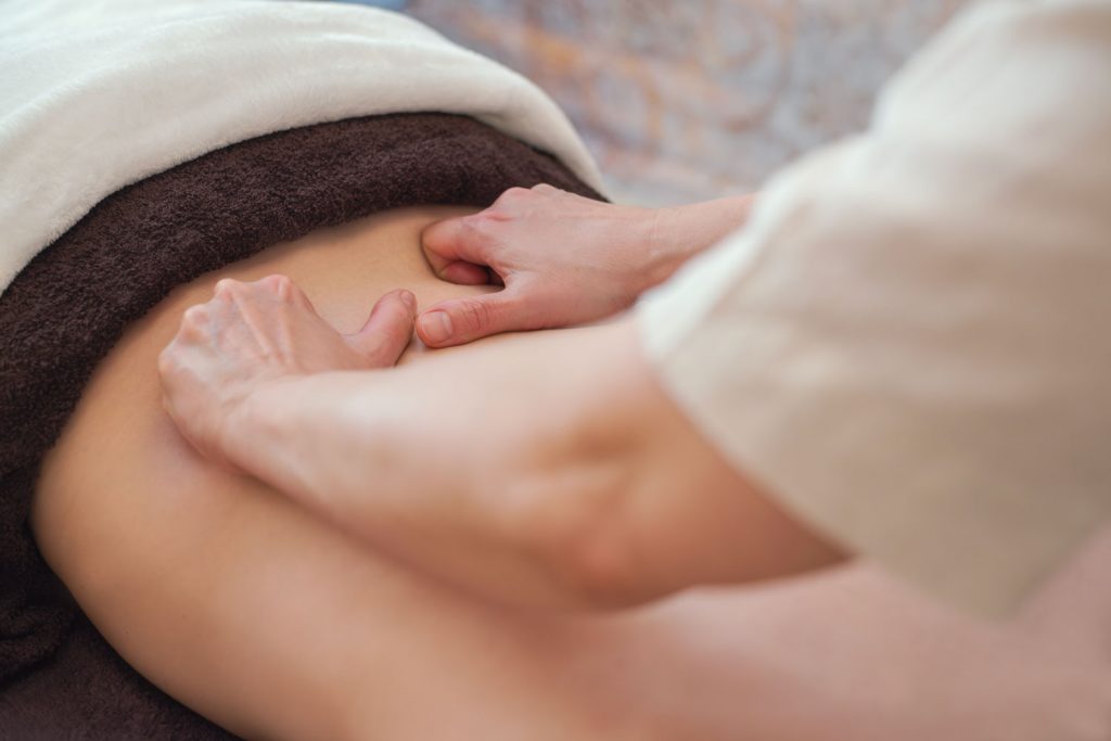 Mit sanften Streichbewegungen der Daumen massiert Susan Mehr den unteren Rücken einer Kundin während der Sabai - Thailändische Massage