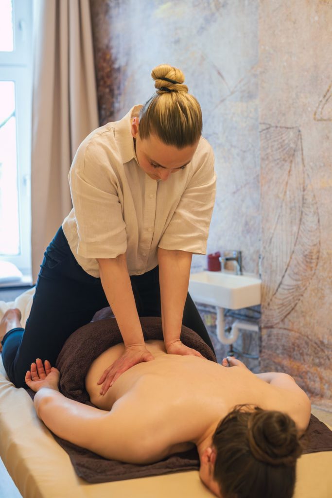 Im Rahmen der thailändischen Massage behandelt Susan Mehr auf der Liege kniend den Rücken einer auf dem Bauch liegenden Kundin