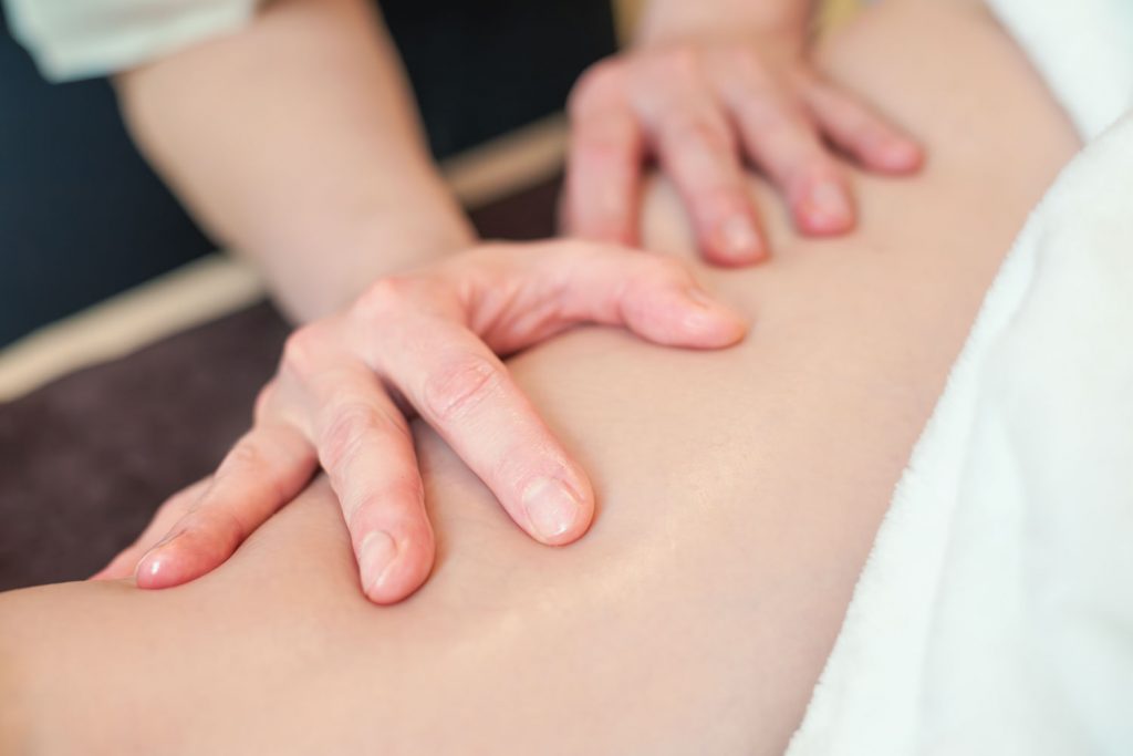 Susan Mehr massiert mit beiden Händen den Oberschenkel einer Kundin während der Aromaölmassage