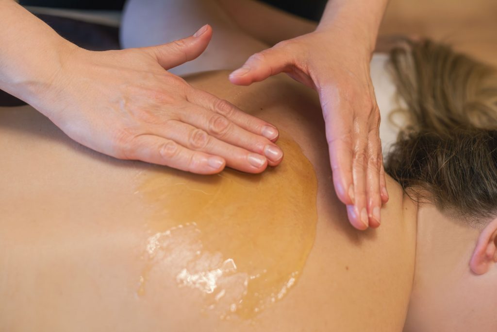 Der Honig wird von Susan Mehr in den oberen Rücken der Kundin einmassiert während der Honigmassage