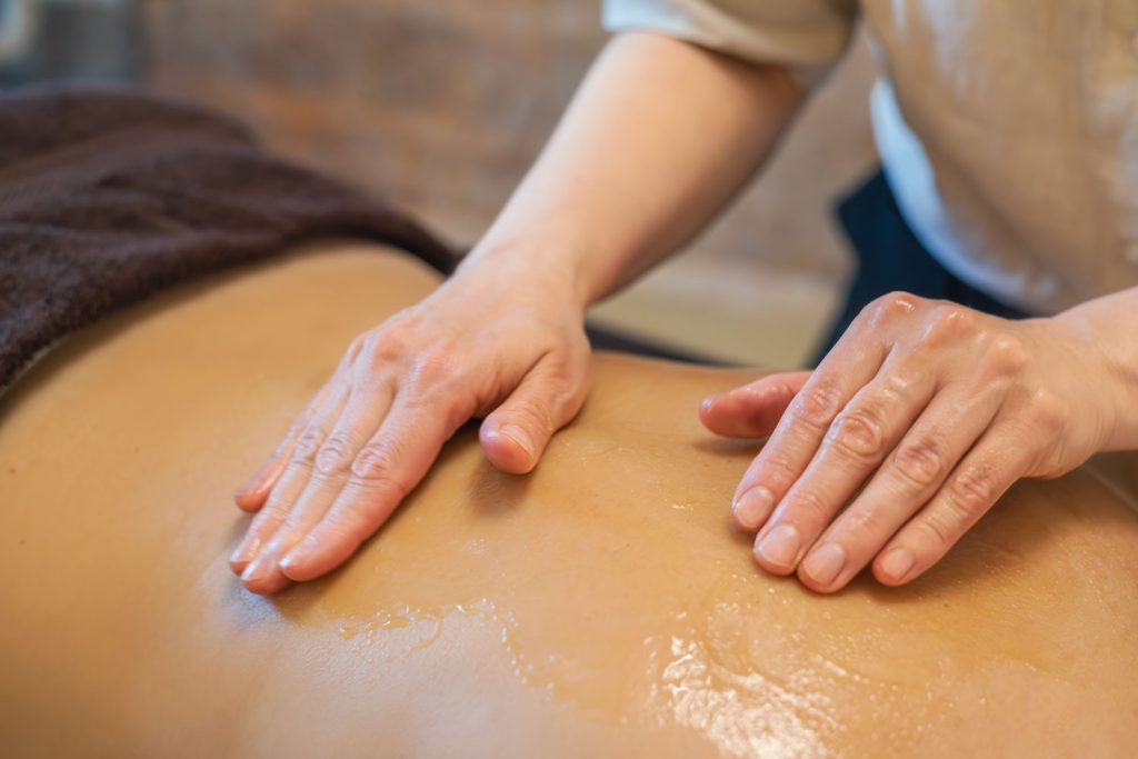 Susan Mehr massiert den Rücken mit Honig einer auf dem Bauch liegenden Kundin während der Honigmassage