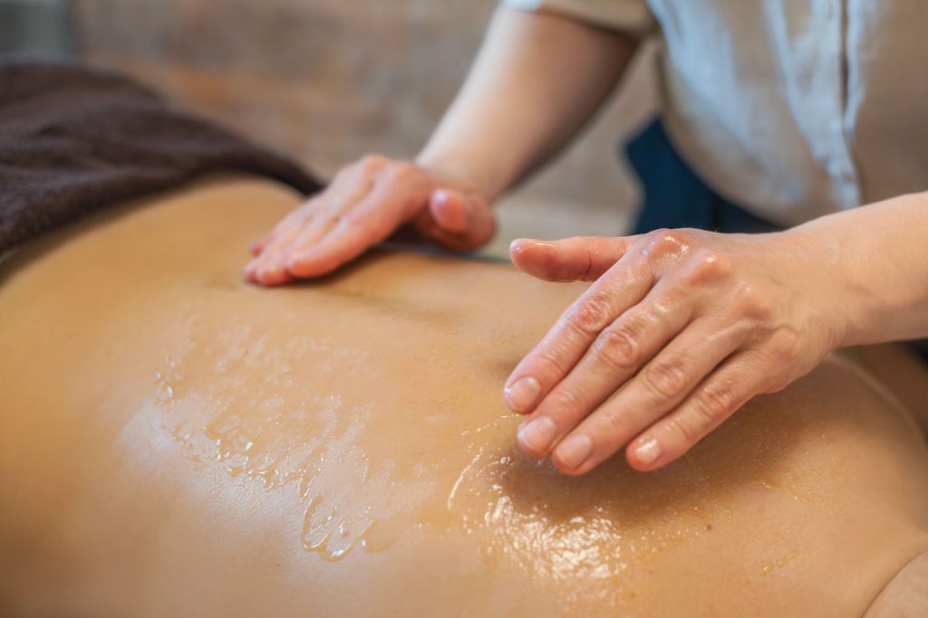 Mittels einer Zupftechnik löst Susan Mehr Verspannungen im Rücken einer Kundin während der Honigmassage